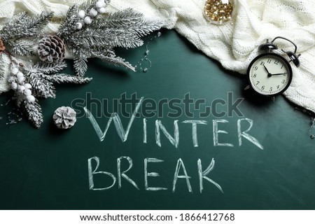 Flat lay composition of Christmas decorations, knitted plaid and alarm clock on school blackboard with phrase Winter Break