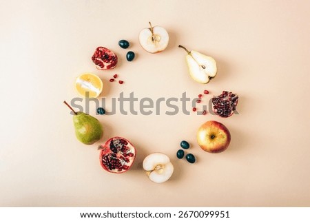 Flat lay composition with circle made of fresh fruits including apple, pear, pomegranate, lemon and grapes on pastel beige background with copy space. Top view