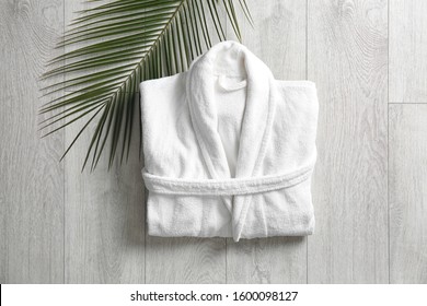 Flat lay composition with clean folded bathrobe on light wooden background