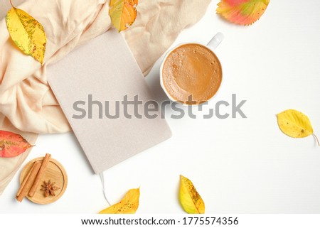 Flat lay composition with coffee cup, notebook, beige fabric and fallen leaves on white background. Autumn, fall concept.