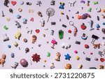 Flat lay composition of colorful small toys, trinkets, charms, letters, animals and shapes scattered on a pastel background. Playful childhood concept, creativity, diversity, fun, copy space.