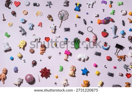 Flat lay composition of colorful small toys, trinkets, charms, letters, animals and shapes scattered on a pastel background. Playful childhood concept, creativity, diversity, fun, copy space.