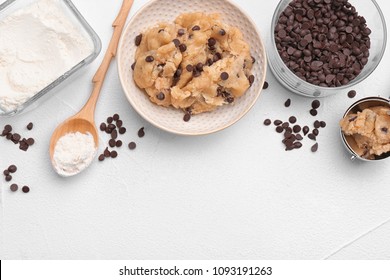 Flat lay composition with cookie dough, chocolate chips and flour on light background - Powered by Shutterstock