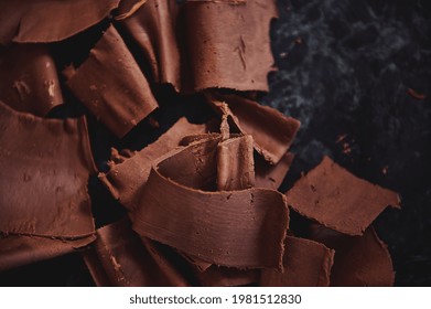Flat lay composition with cooled chocolate mass collected with a confectionery scraper on a marble surface. World chocolate Day