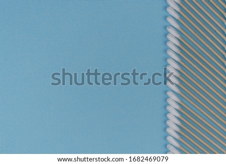Flat lay composition with cotton swabs on blue background. natural cotton sticks made from cotton and cane. hygiene and sanitation. Top view ear sticks. 
