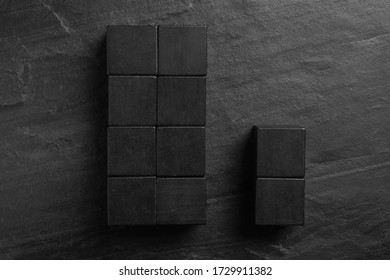 Flat lay composition with cubes on black slate background. Pareto principle concept