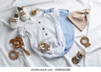 Flat Lay Composition With Cute Baby Clothes And Accessories On White Bedsheet