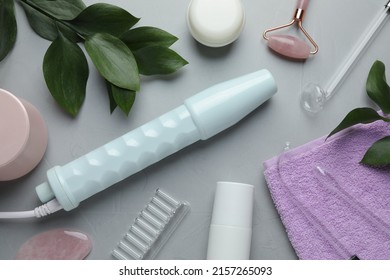 Flat Lay Composition With Darsonval, Rose Quartz Facial Roller And Gua Sha On Grey Table