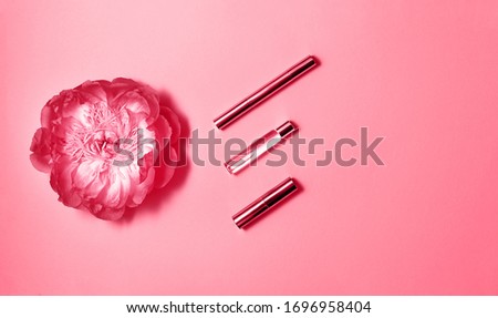 Flat lay composition with decorative makeup products, perfume and peony on pink background. Makeup and beaty concept. Copy space.