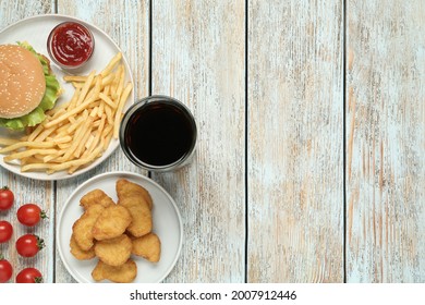 Flat lay composition with delicious fast food menu on white wooden table. Space for text