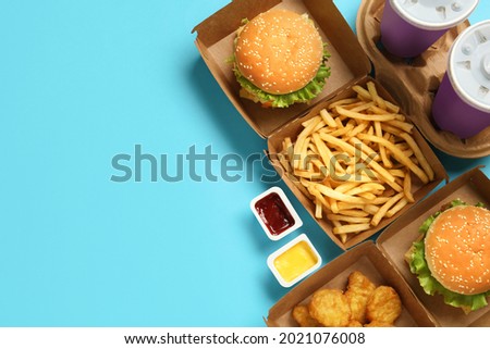 Flat lay composition with delicious fast food menu on light blue background. Space for text