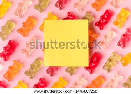 Flat lay composition with delicious jelly bears and empty card on color background. Space for text