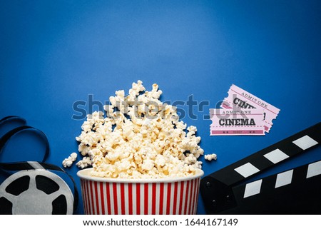 Flat lay composition with delicious popcorn and cinema items on blue background