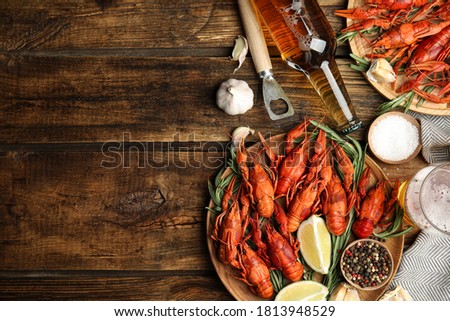 Flat lay composition with delicious red boiled crayfishes on wooden table, space for text