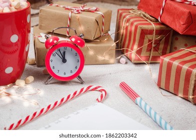 Flat lay composition with diary book for writing down New Year's plans with red Christmas  decorations, cup of cocoa with marshmallows, alarm and gifts. Planing New Year. Goals in notebook 