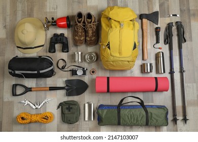 Flat lay composition with different camping equipment on wooden background. Traveler set