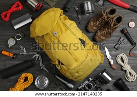 Flat lay composition with different camping equipment on dark wooden background. Traveler set