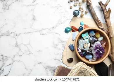 Flat lay composition with different gemstones on white marble background. Space for text