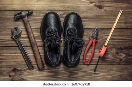 Flat lay composition with different industrial working tools and instruments, safety equipmen on wooden background. Top view