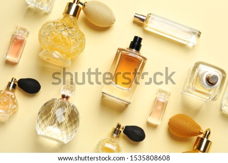 Flat lay composition with different perfume bottles on light yellow background