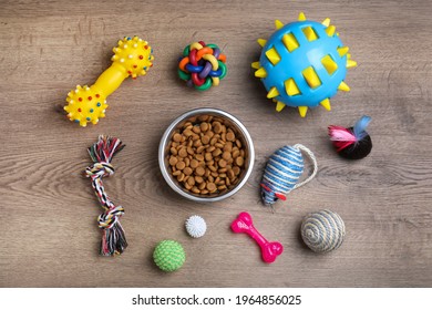 Flat Lay Composition With Different Pet Toys And Feeding Bowl On Wooden Background