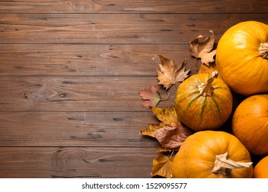 Flat lay composition with different ripe pumpkins on wooden background, space for text. Holiday decoration