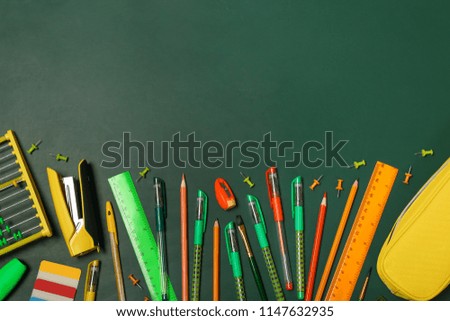 Flat lay composition with different school stationery on chalkboard surface