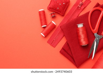 Flat lay composition with different sewing supplies on coral background. Space for text