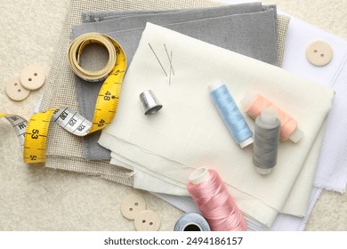 Flat lay composition with different sewing supplies on light textured table