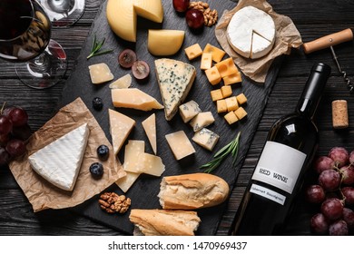 Flat lay composition with different types of delicious cheese on slate board