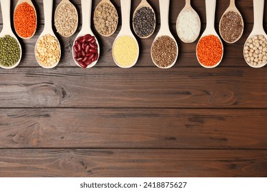 Flat lay composition with different types of legumes and cereals on wooden table, space for text. Organic grains