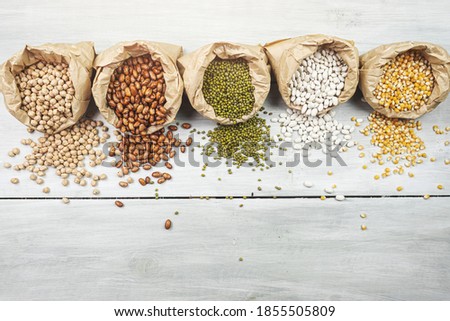 Flat lay composition with different types of legumes and cereals on gray wooden table, space for text. Organic grains