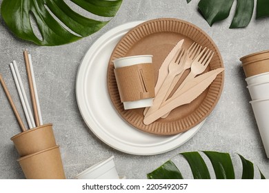 Flat lay composition with disposable tableware and monstera leaves on light grey background