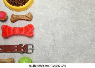 Flat Lay Composition With Dog Collar, Toys And Food On Grey Table. Space For Text