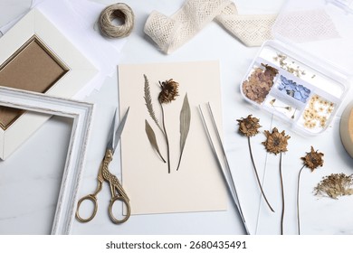 Flat lay composition with dry flowers and paper on white marble table