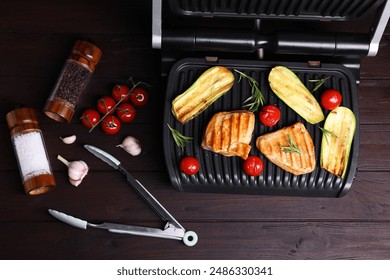 Flat lay composition with electric grill and different products on wooden table