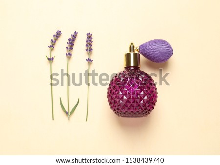 Flat lay composition with elegant perfume and beautiful flowers on beige background