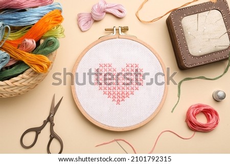 Flat lay composition with embroidery and different sewing accessories on beige background