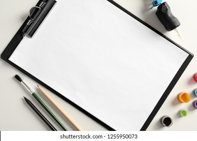 Flat lay composition with empty sheet of paper and tattoo machine on white background. Space for text - Shutterstock ID 1255950073