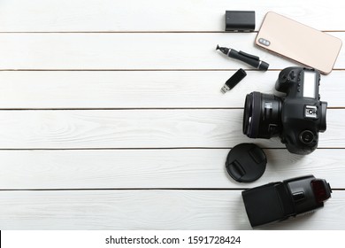 Flat lay composition with equipment for professional photographer on white wooden table. Space for text