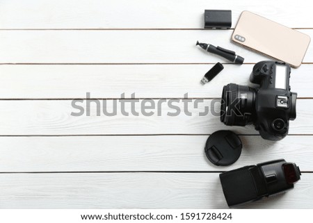 Flat lay composition with equipment for professional photographer on white wooden table. Space for text