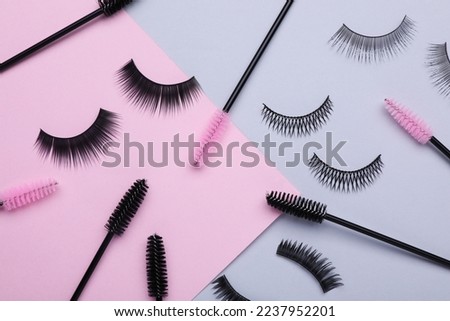 Flat lay composition with fake eyelashes and brushes on color background