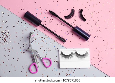 Flat lay composition with false eyelashes and cosmetic tools on color background