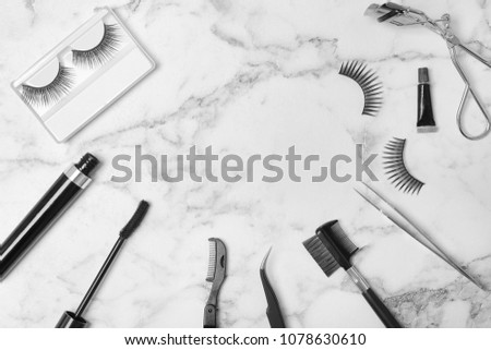 Flat lay composition with false eyelashes and cosmetic tools on light background