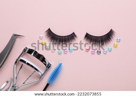 Flat lay composition with false eyelashes and cosmetic tools on pink background