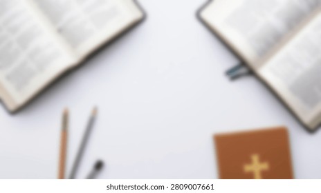 A flat lay composition featuring two open Bibles and a small brown holy book with a golden cross symbol, alongside writing utensils on a clean white surface.