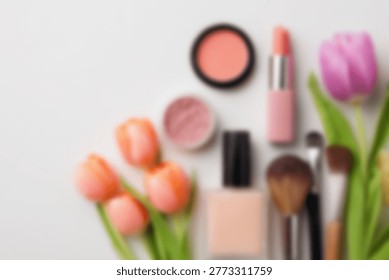 A flat lay composition featuring various makeup items like lipstick, foundation, blush, and brushes, artfully arranged with vibrant tulips on a clean white background.
