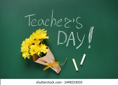 Flat lay composition with flowers and inscription TEACHER'S DAY on green chalkboard