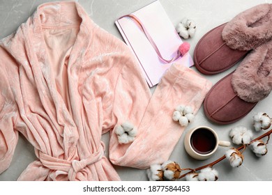 Flat lay composition with fluffy slippers and robe on grey background. Comfortable home outfit