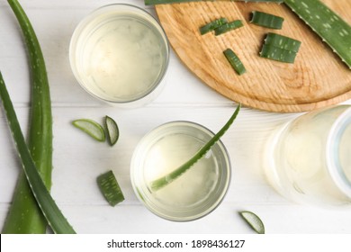 Flat lay composition with fresh aloe drink and leaves on white wooden table